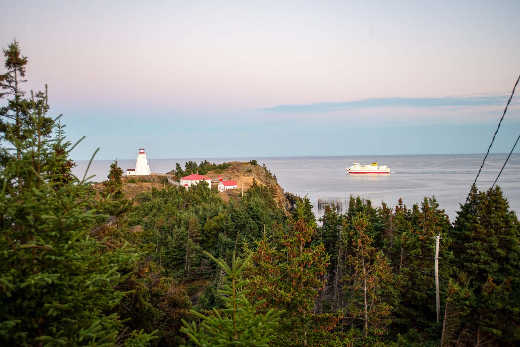 View of the Swallowtail Lighthouse with a passing ferry on Grand Manan Island, NB.