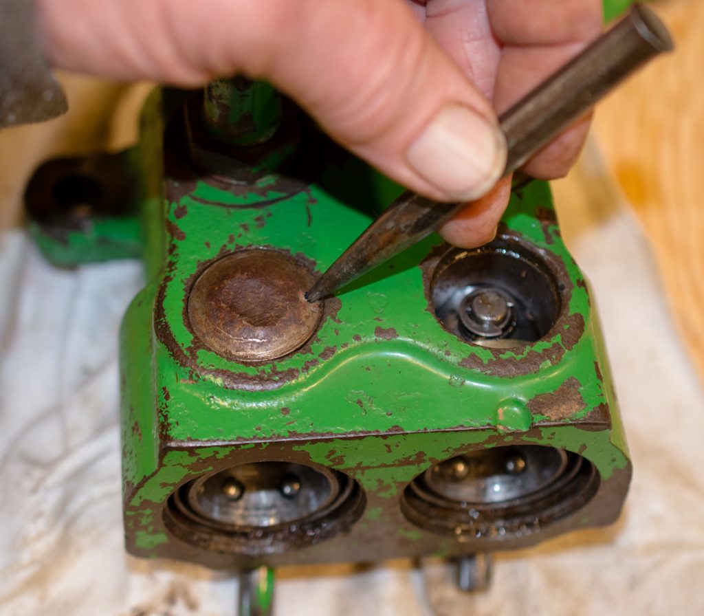 Photo removing the soft metal caps of a JD Breakaway Coupler on a JD 1640/2040 tractor.