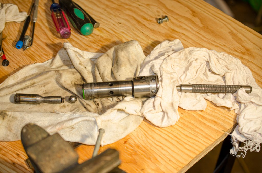 Photo showing driving out the piston thru the end of the coupler of a John Deere 1640/2040 Breakaway Coupler.